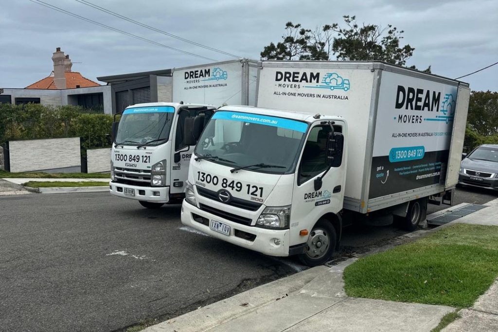 Two Dream Movers trucks parked kerbside on a quiet residential street